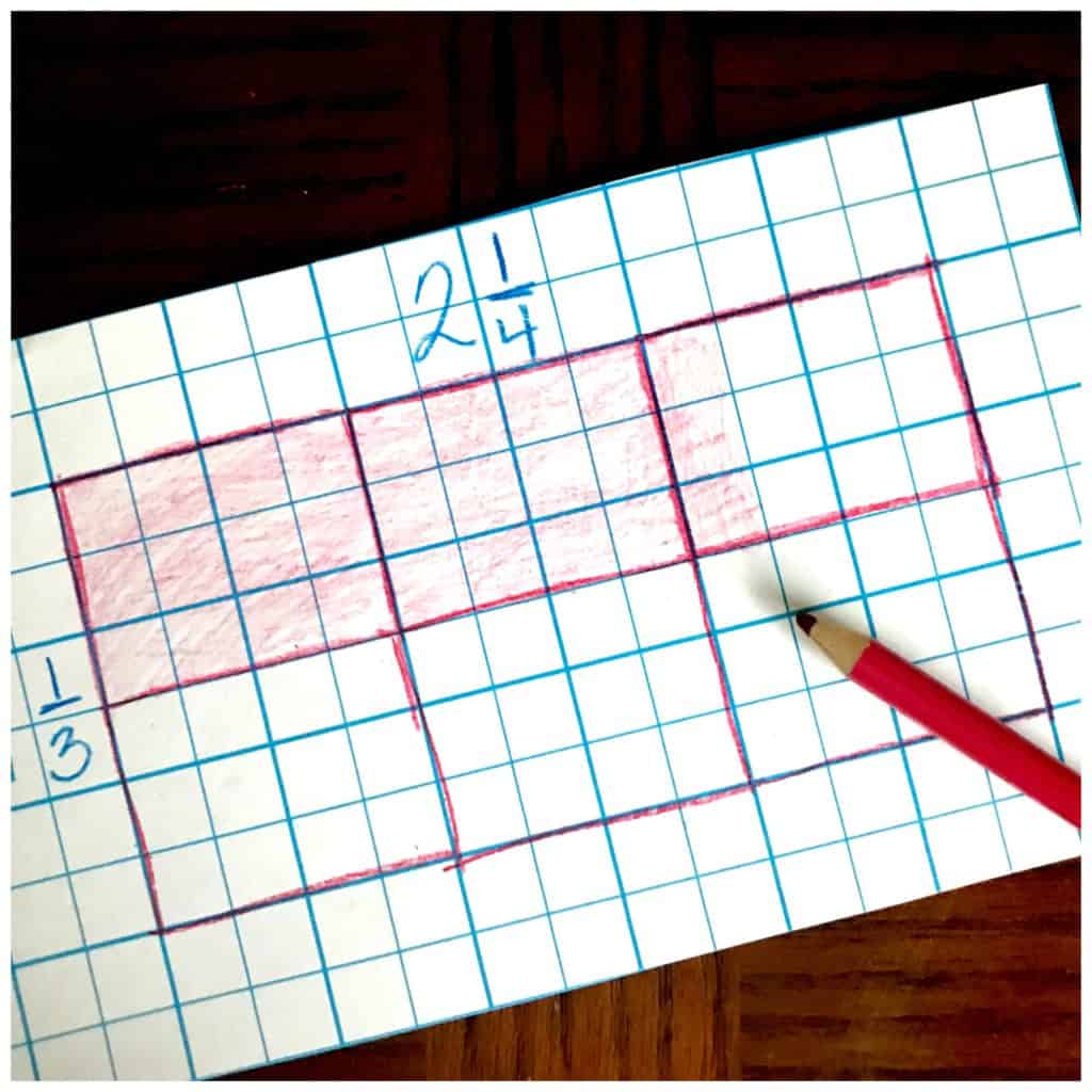 Multiplication arrays game worksheet on a wooden table with a pink pencil crayon. 
