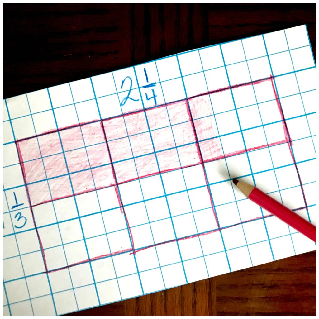 Multiplication arrays game worksheet on a wooden table with a pink pencil crayon. 
