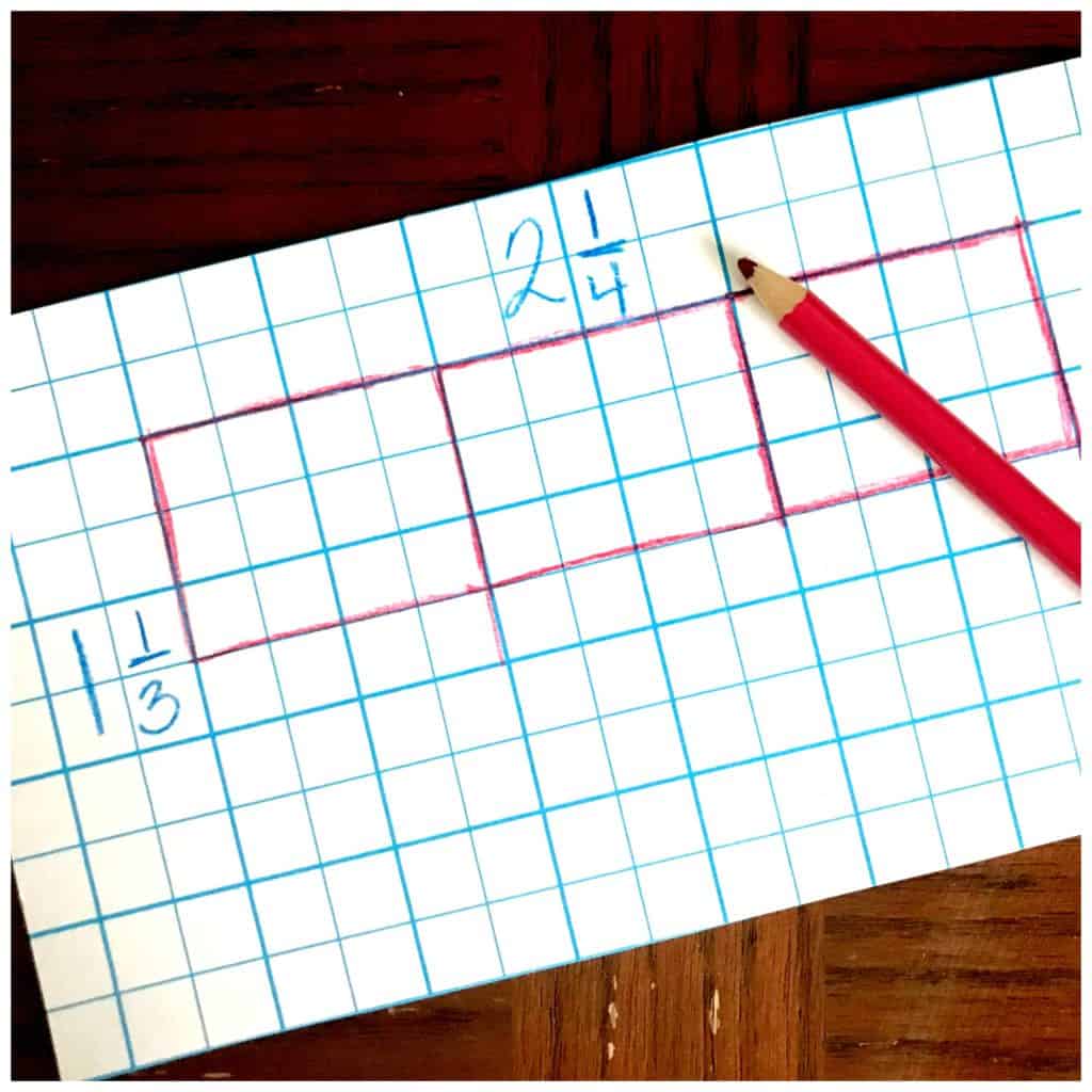 Multiplication arrays game worksheet on a wooden table with a pink pencil crayon. 
