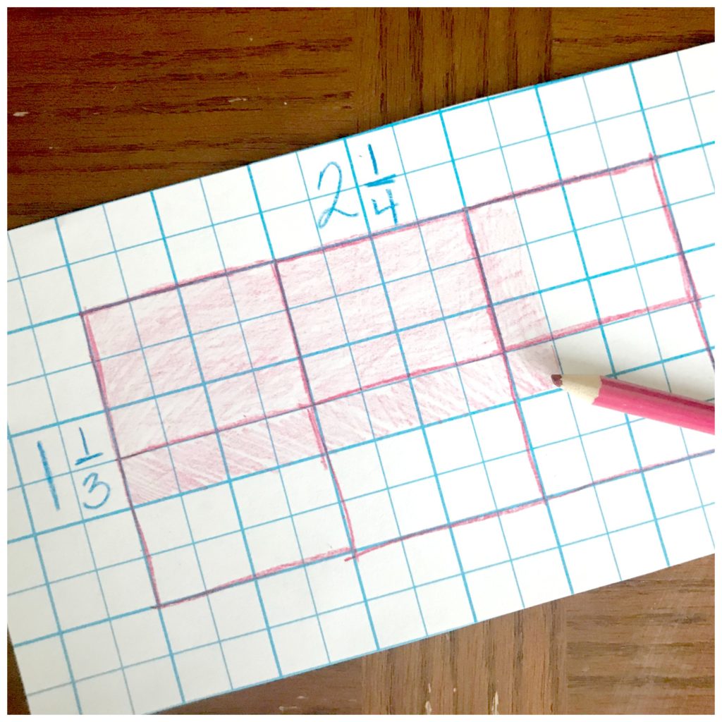 Multiplication arrays game worksheet on a wooden table with a pink pencil crayon. 
