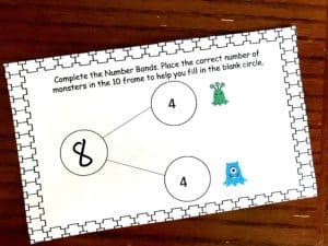 Number bonds with monsters worksheet on a wooden background. 