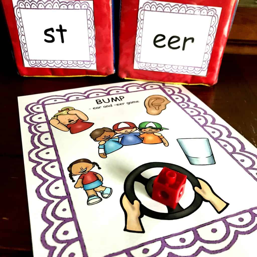 EAR word phonics game with large dice. One dice says, "st" and the other dice says "eer". There is a worksheet with various pictures on it. 