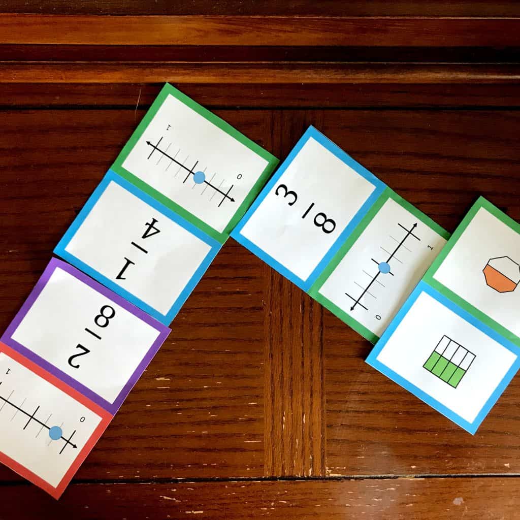 Fraction dominoes are laid out on the wooden floor. 