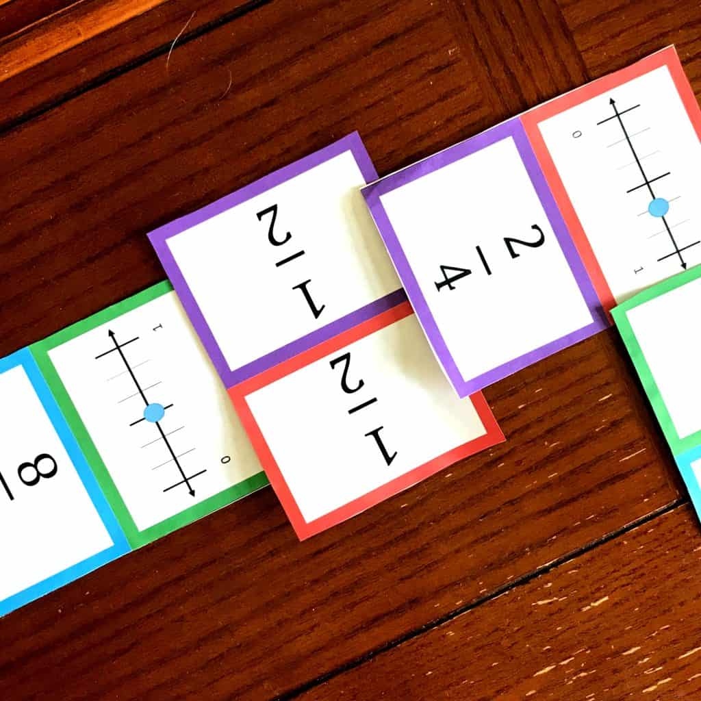 Fraction dominoes are laid out on the wooden floor. 