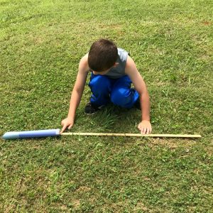 STEM Measurement Activities for 2nd Grade with a little boy measuring the distance a paper javelin was thrown. 