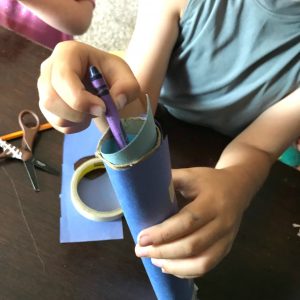 STEM Measurement Activities for 2nd Grade with a little boy filling his paper javelin with crayons to add weight to it. 