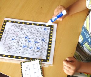 A child solving a number puzzle by using a blue marker to cross out numbers.  