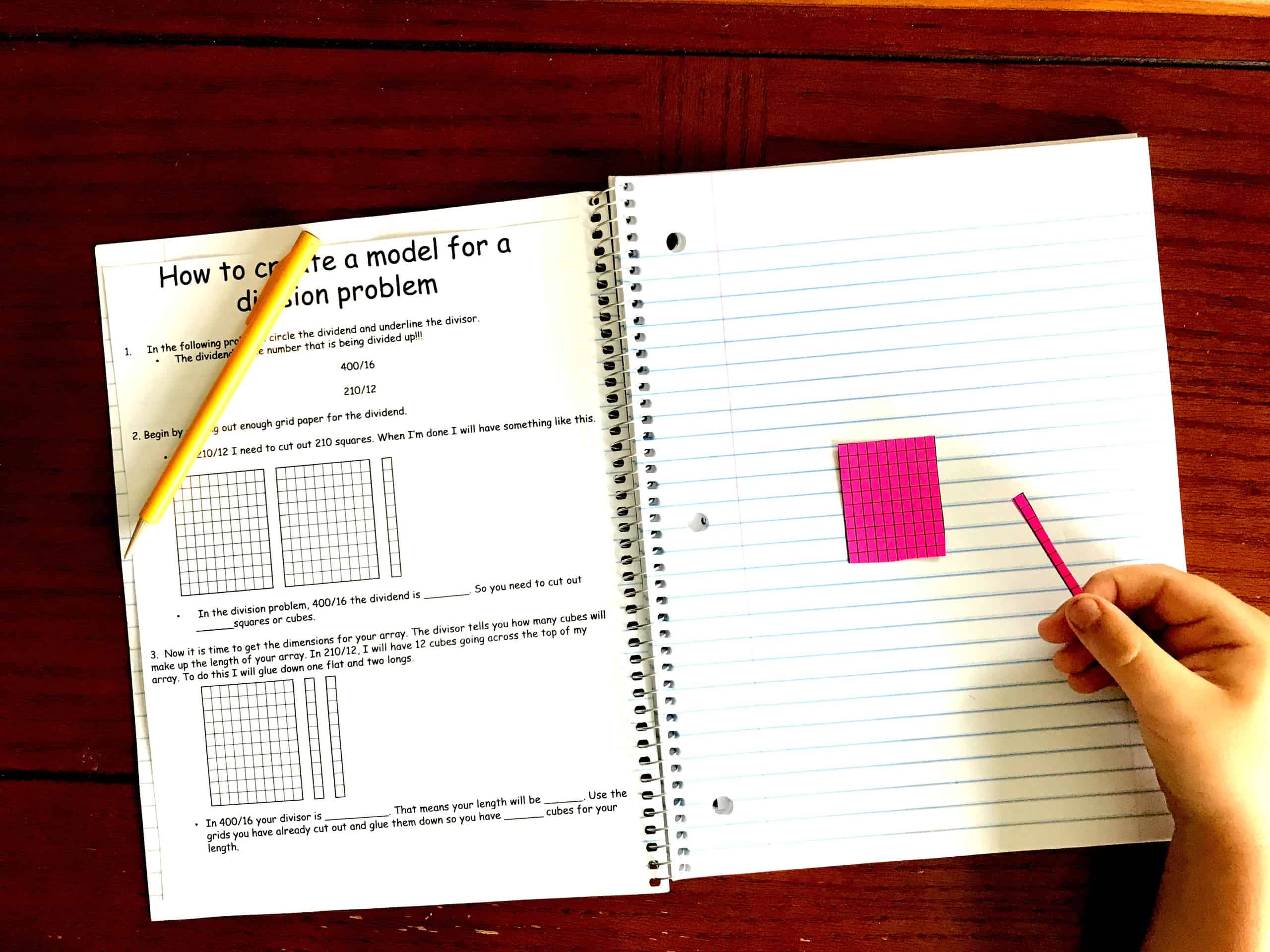 Division with arrays interactive notebook with a pink grid on lined paper. A hand is holding a line of grid paper. 