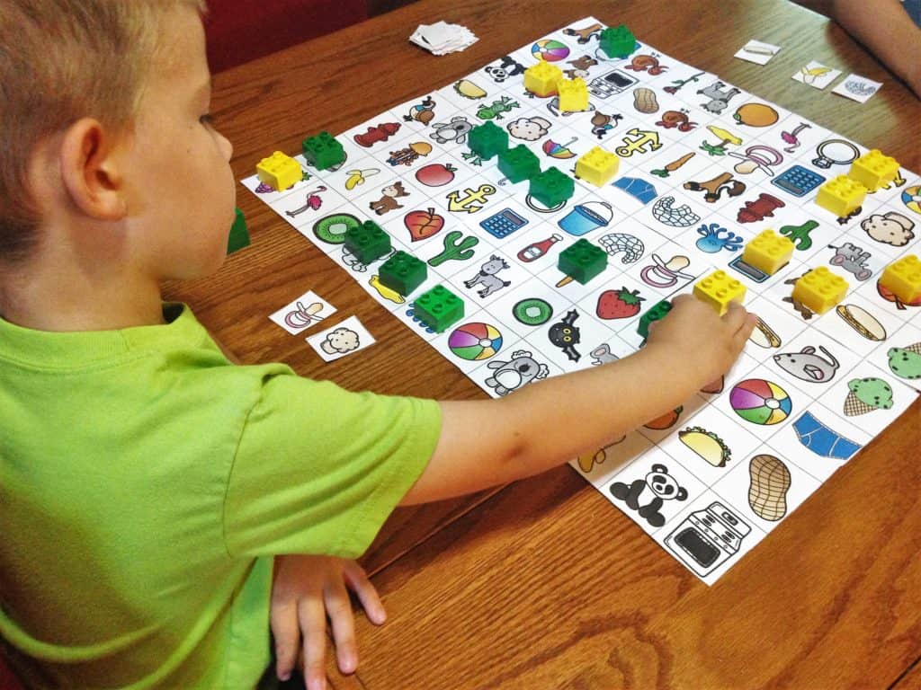 A little boy playing a living vs non living game with lego pieces. 