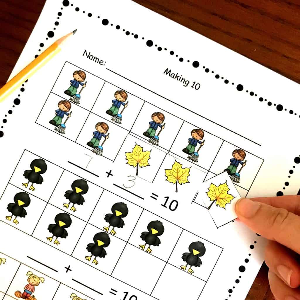 Adding to 10 worksheet with leaves and black birds on it. A hand is adding a yellow leaf to the worksheet. 