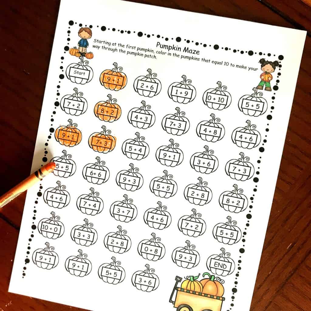 Adding to 10 worksheet with some pumpkins colored in orange and an orange crayon laying on the worksheet. 