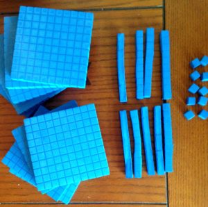 Blue base ten blocks are made into cubes, lines, and singles. 