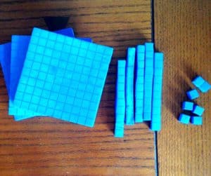 Blue base ten blocks are made into cubes, lines, and singles. 