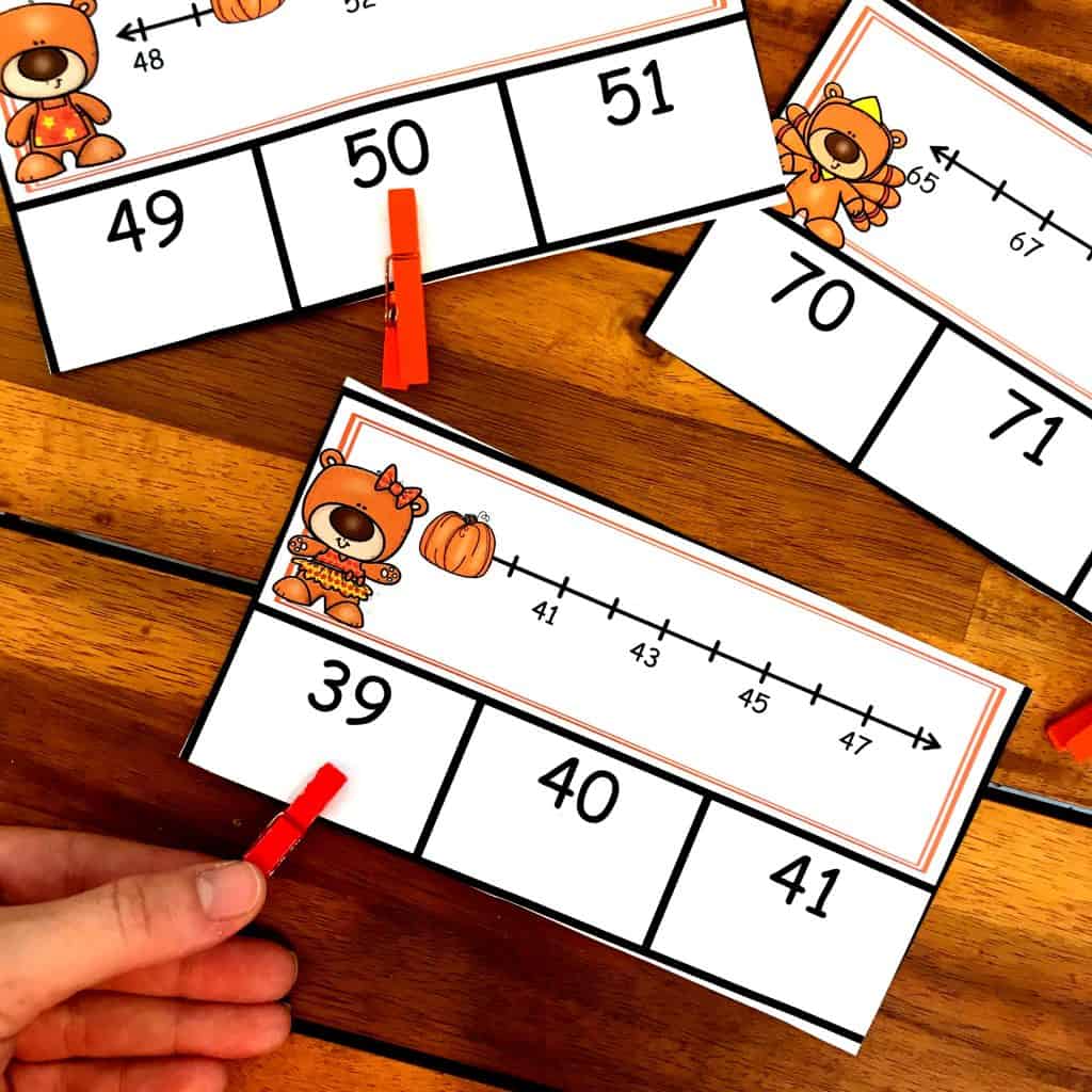 Number line clip cards with clothespins on the answer with a wooden background. 