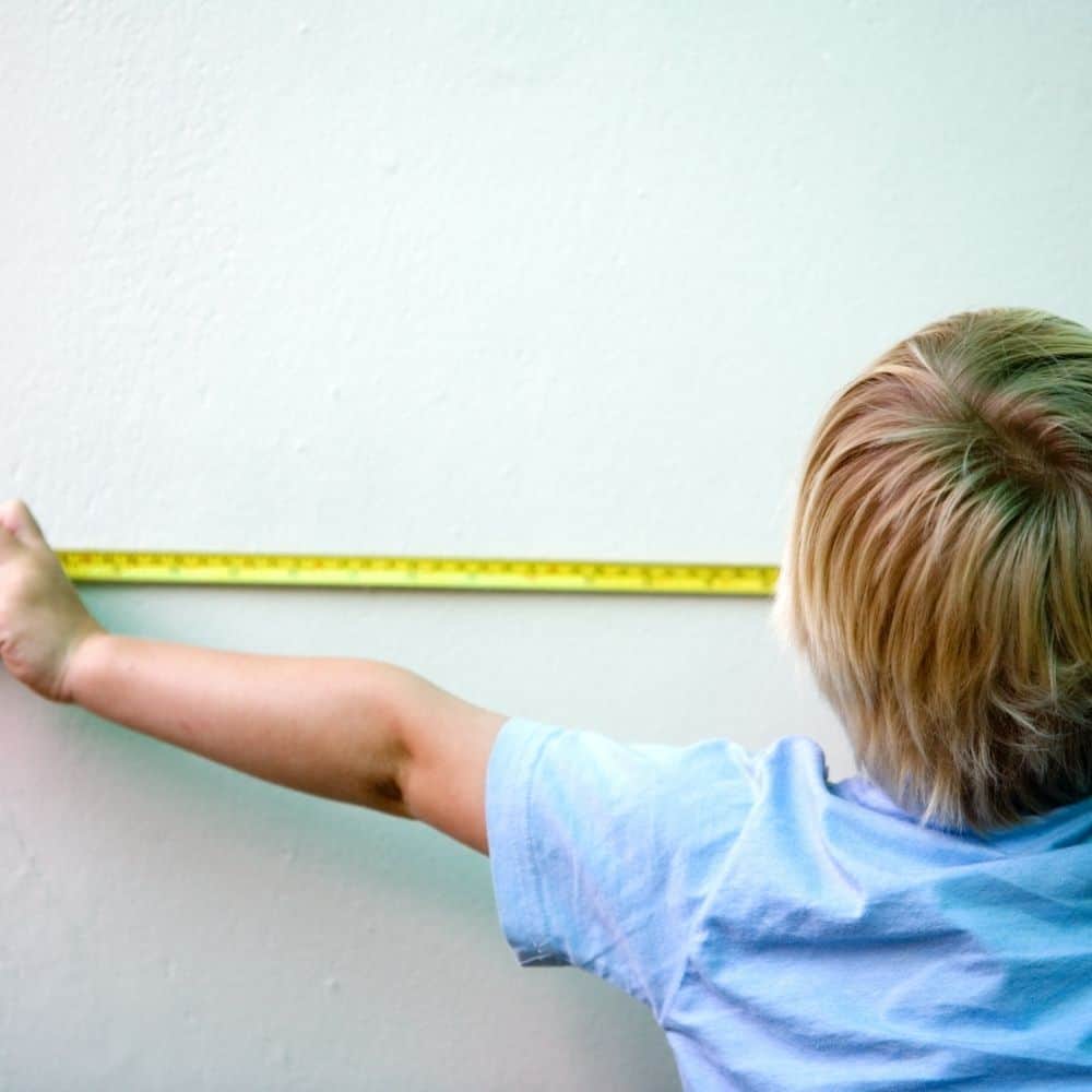child using a tape measure to measure a wall